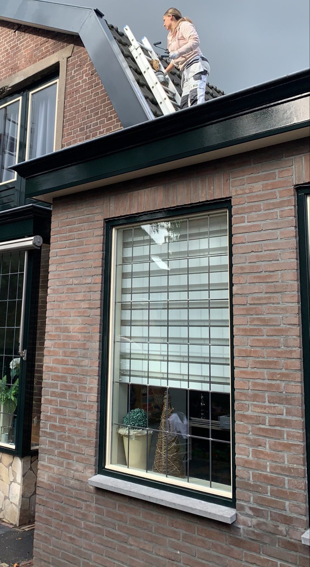 Woning in de steigers, met een schilder op het dak
